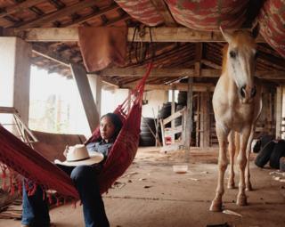 امرأة مستلقية على أرجوحة بجوار حصان