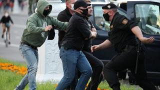 ضباط الشرطة يرتدون أقنعة واقية تحتجز متظاهراً أثناء تجمع حاشد في مينسك ، روسيا البيضاء