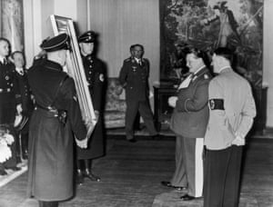 المارشال الألماني هيرمان جورينج (الثاني من اليمين) معجب بلوحة قدمها له أدولف هتلر (يمين) بمناسبة عيد ميلاده الخامس والأربعين.