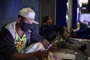 رجل يتحقق من هاتفه خارج فرع Caixa Econômica Federal في بيلو هوريزونتي.
