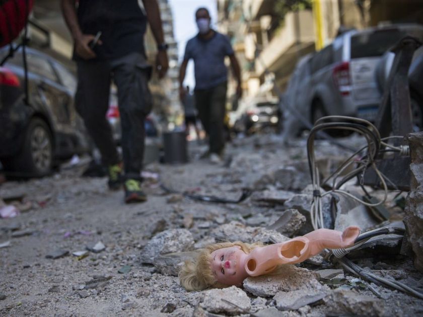 أشخاص يمشون بجوار دمية طفل انفجرت من مبنى قريب بعد انفجار هائل وقع قبل يوم ، 5 أغسطس ، 2020 في بيروت ، لبنان.