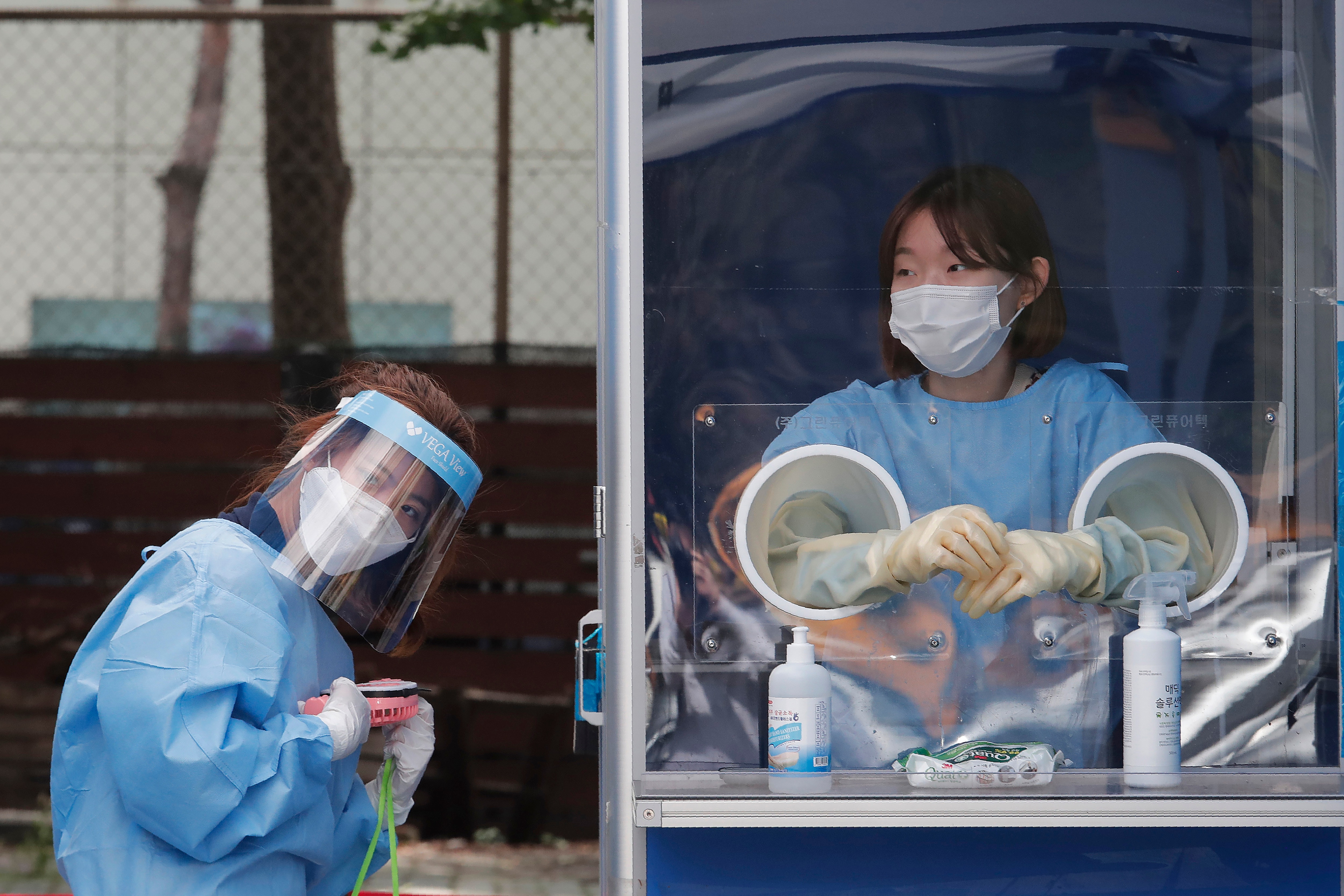 عامل طبي يحمل مروحة محمولة وسط الحرارة الشديدة أثناء اختبار ضباط الشرطة لـ COVID-19 في عيادة مؤقتة في سيول ، جنوب كوريا