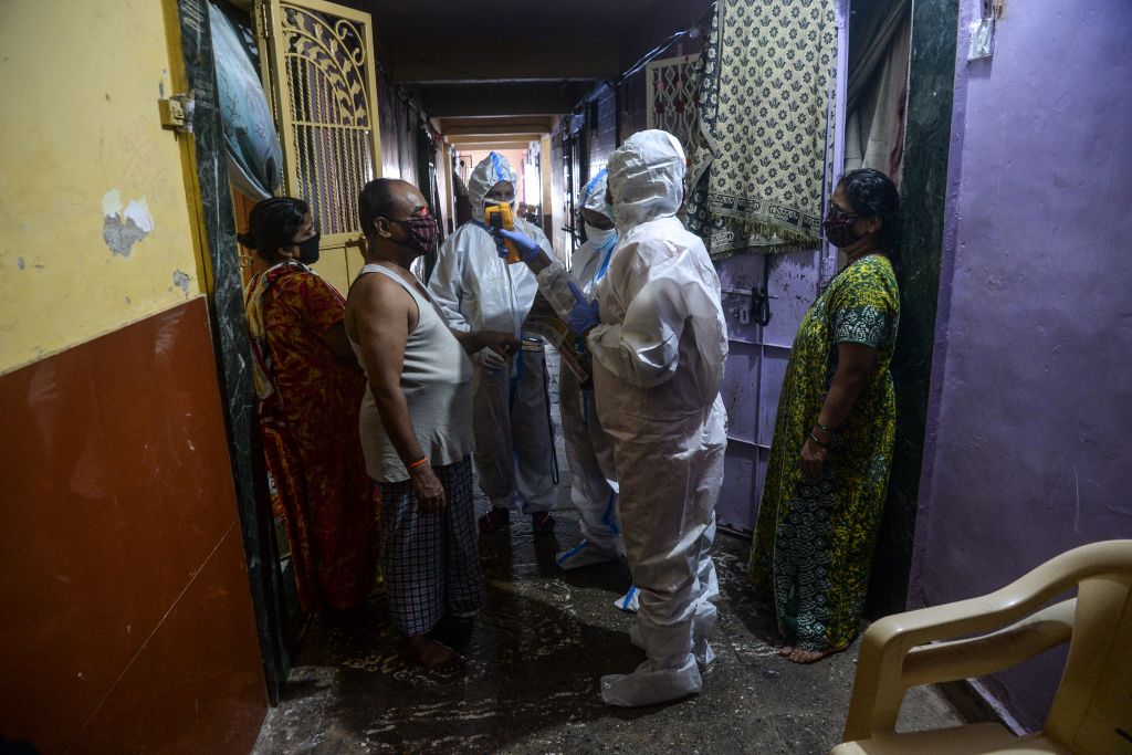 عامل صحي يتحقق من درجة حرارة جسم مقيم أثناء فحص فيروس كورونا من الباب إلى الباب في أحد الأحياء الفقيرة في مومباي