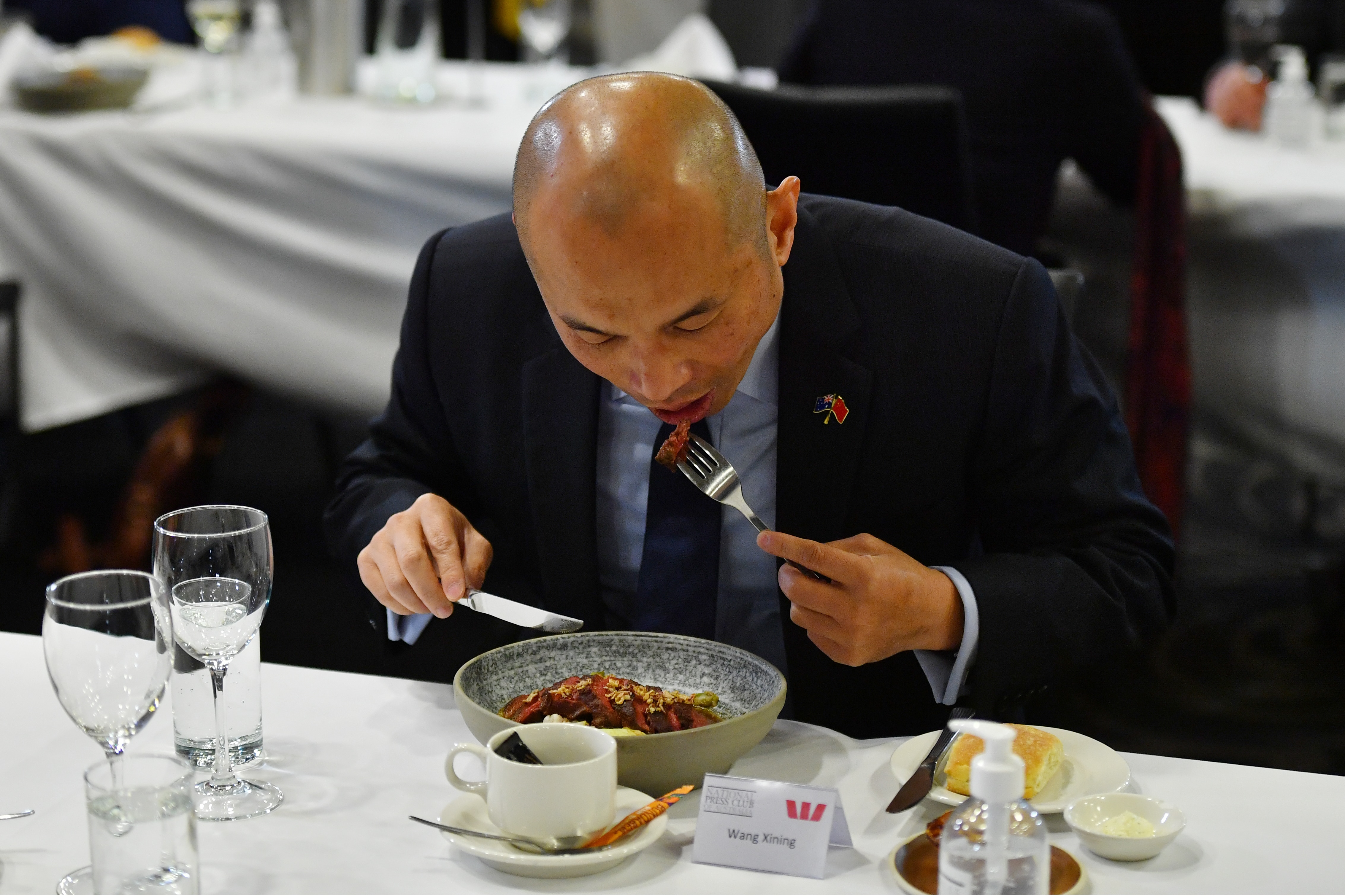 نائب رئيس بعثة السفارة الصينية في أستراليا وانغ شينينغ يأكل اللحم البقري في نادي الصحافة الوطني في كانبيرا.
