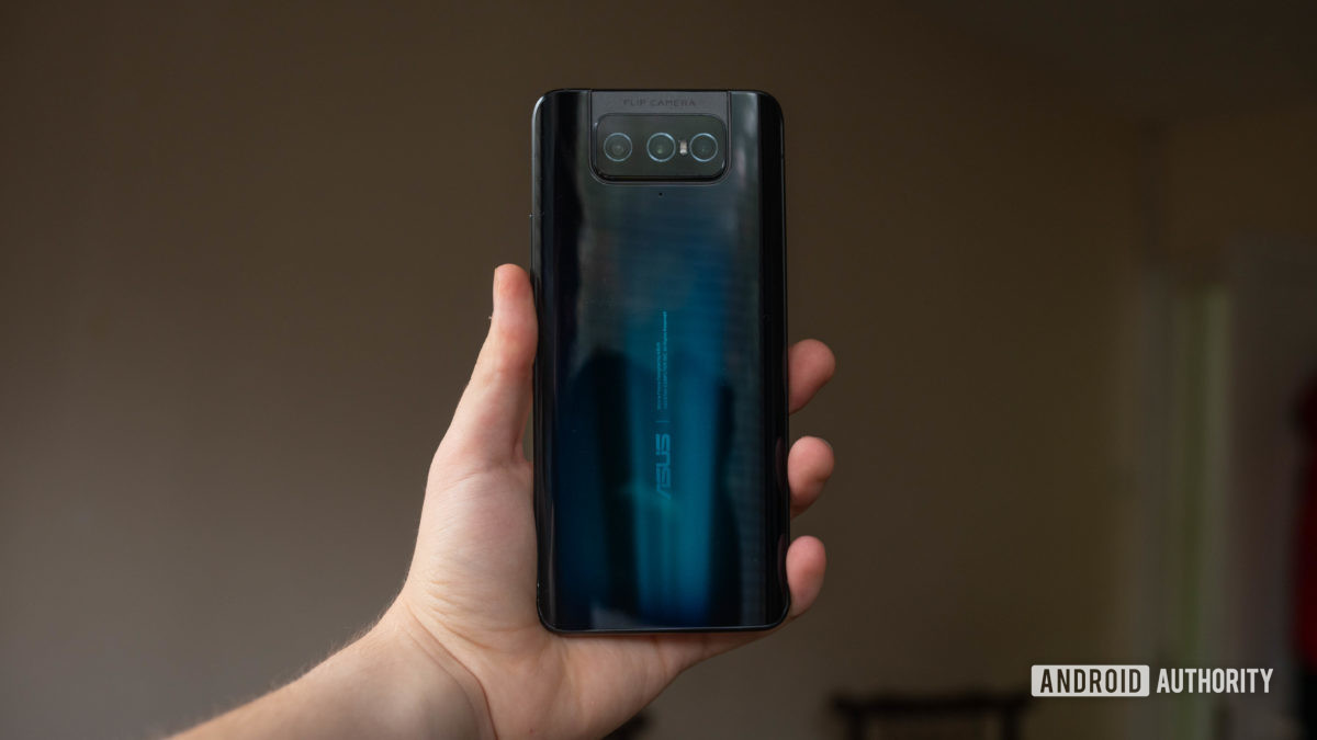 Asus Zenfone 7 في يده يظهر خلف الهاتف