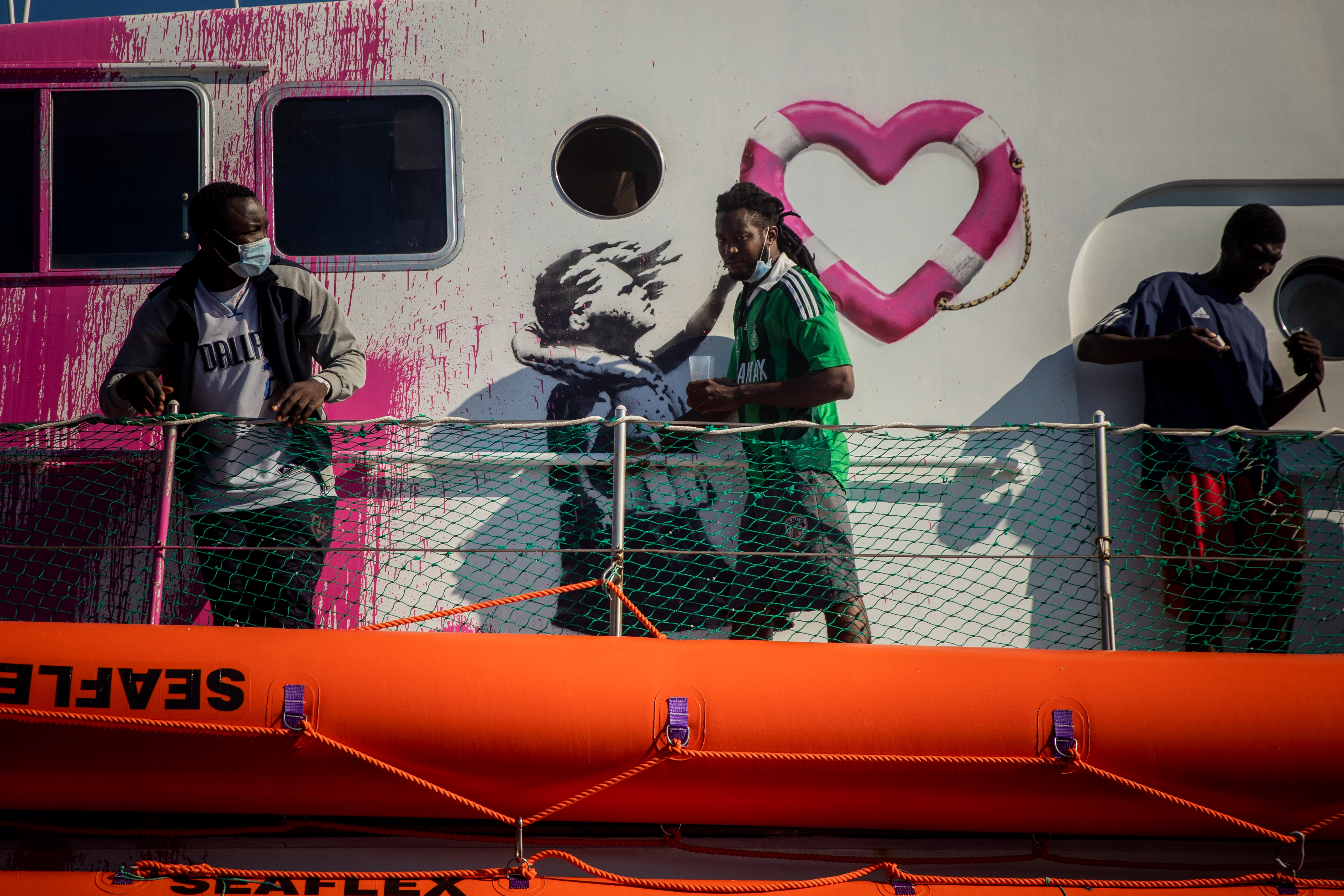 رجل يمر بلوحة للفنان البريطاني بانكسي على سطح سفينة الإنقاذ لويز ميشيل ، بعد إجراء عمليتي إنقاذ.