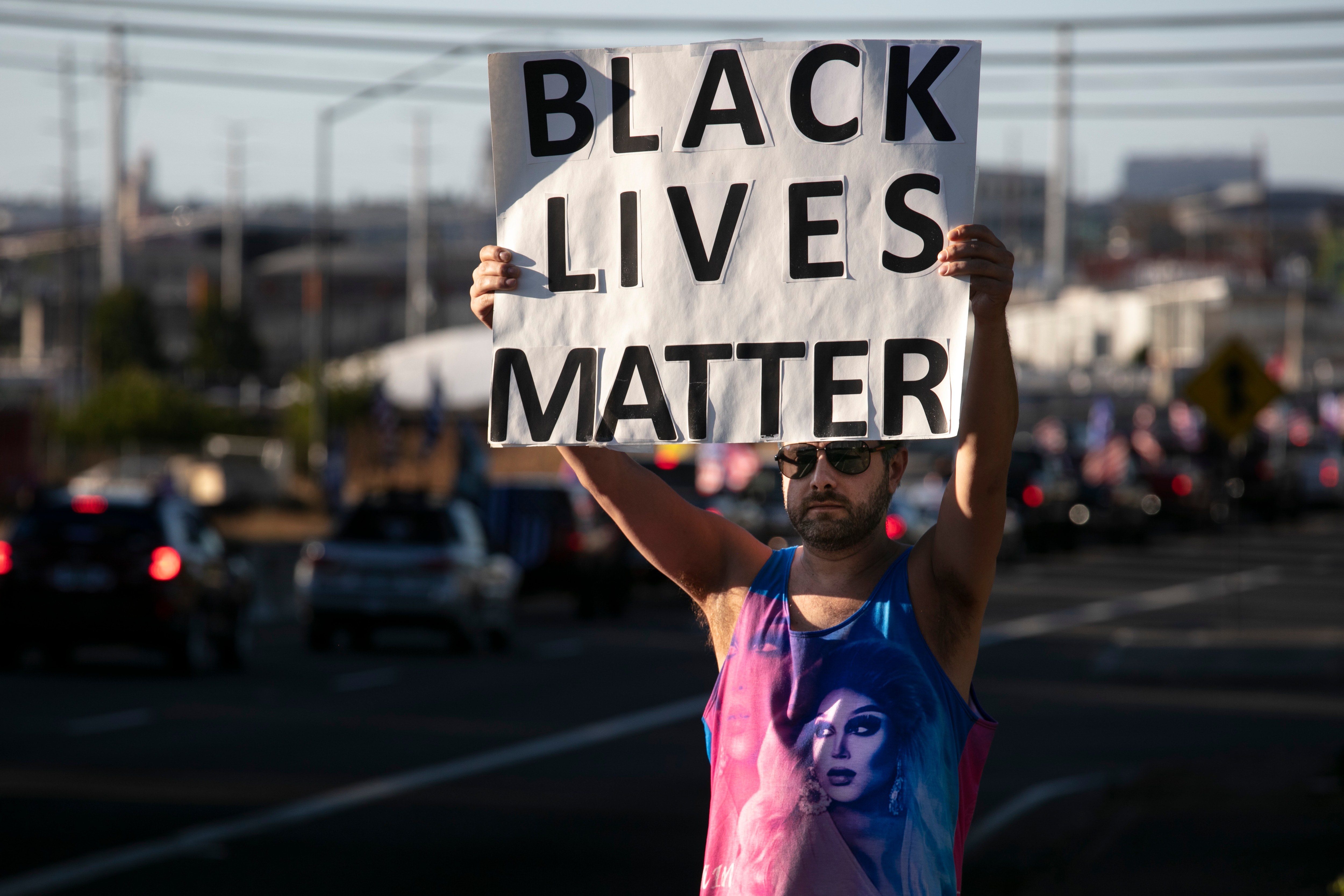 أحد مناصري Black Lives Matter يحمل لافتة بينما يحضر أنصار الرئيس دونالد ترامب مسيرة واستعراض للسيارات في بورتلاند ، أوريغون.
