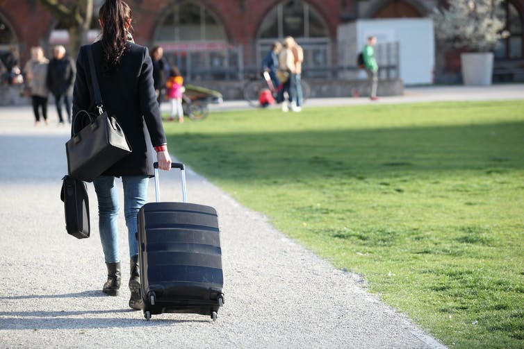 امرأة شابة تمشي بحقيبة سفر