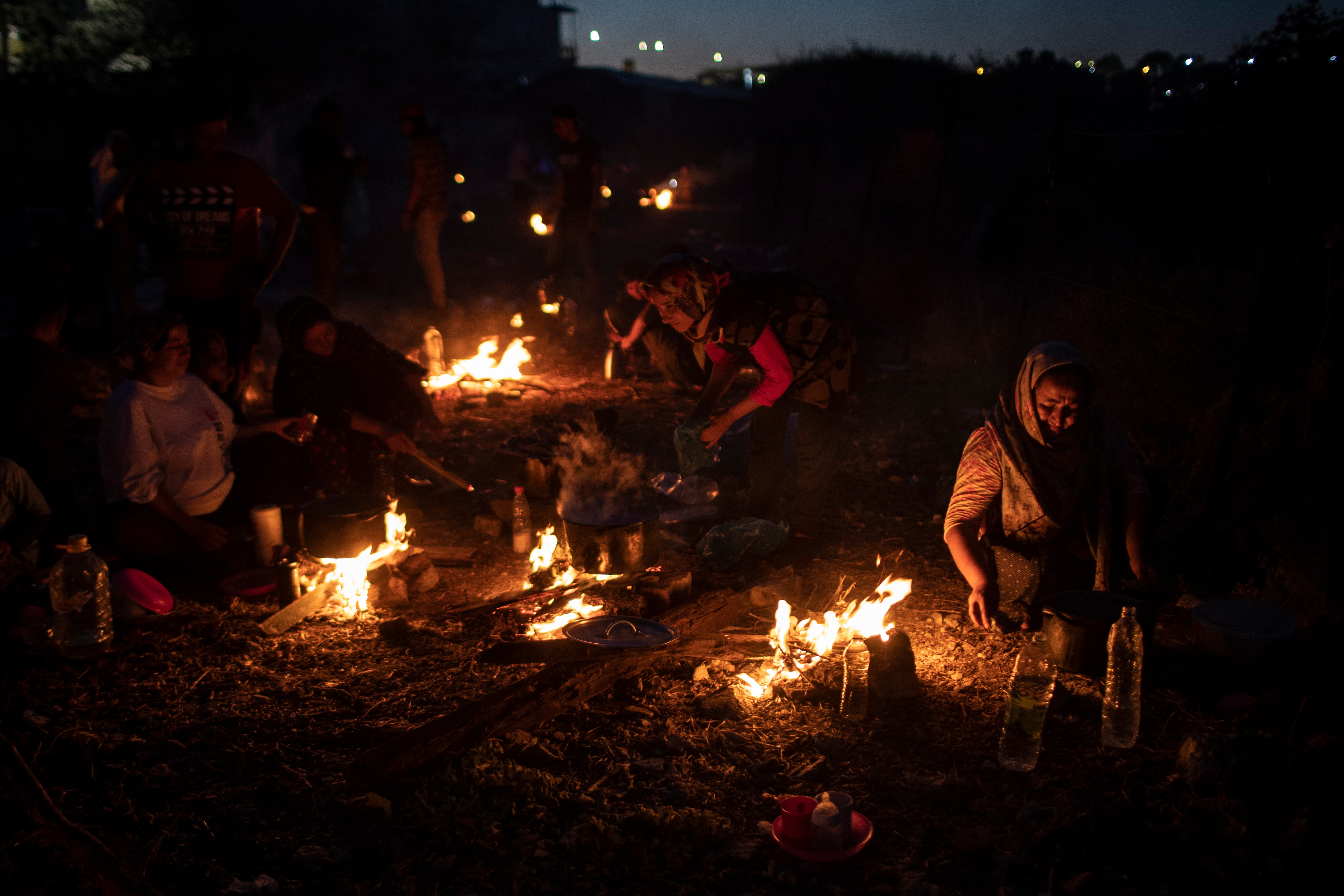 لاجئون ومهاجرون يطبخون الطعام على حرائق مؤقتة بالقرب من مصنع مهجور في جزيرة ليسبوس ، اليونان ، في 11 سبتمبر.